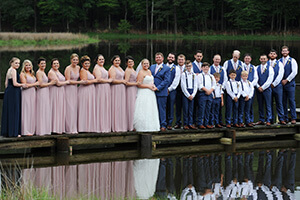 a wedding party with bride and groom pose for a photo on a boat dock walkway